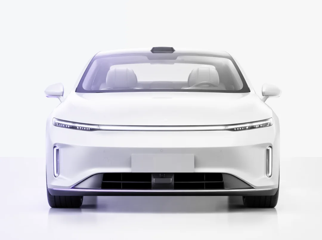 White anodized car photographed head-on, lit by a single amethyst rim light.